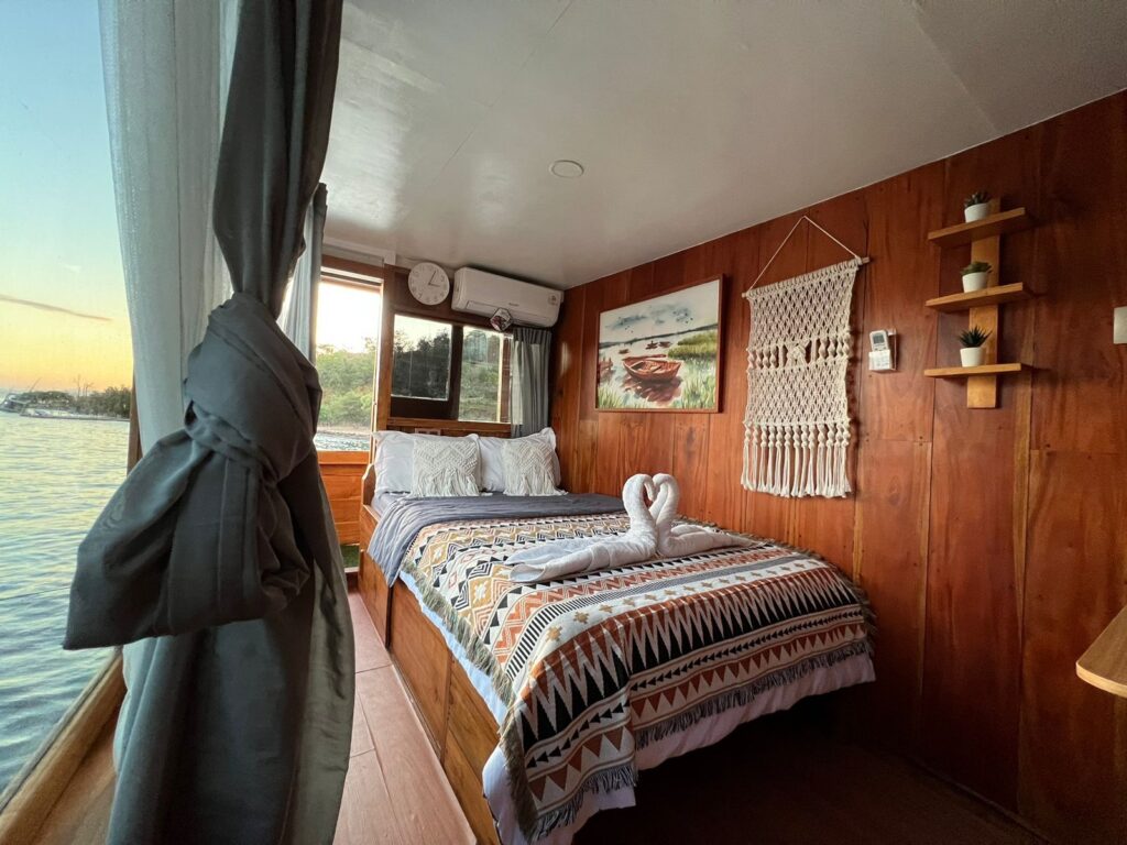 Dinara master suite bed with a patterned throw beside a window at sunset