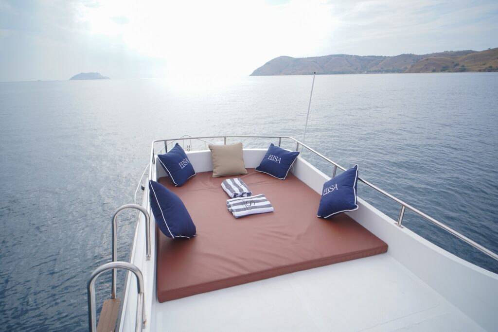 Elisa speedboat bow sun pad with navy cushions and a striped towel