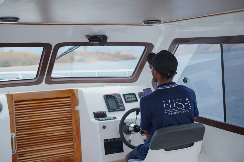 Captain at the helm of the Elisa speedboat checking navigation instruments
