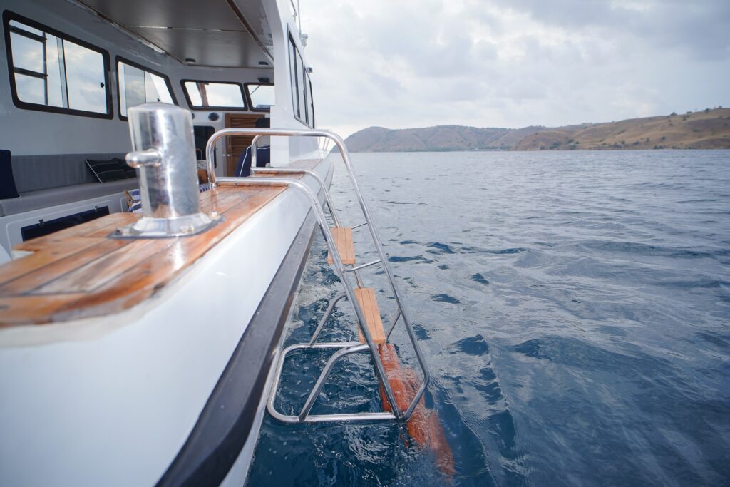 Stainless steel boarding ladder on a speedboat side rail over open water