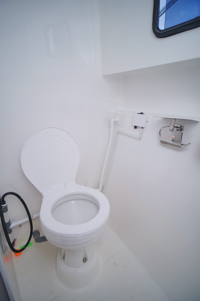 Compact white marine toilet inside a speedboat cabin