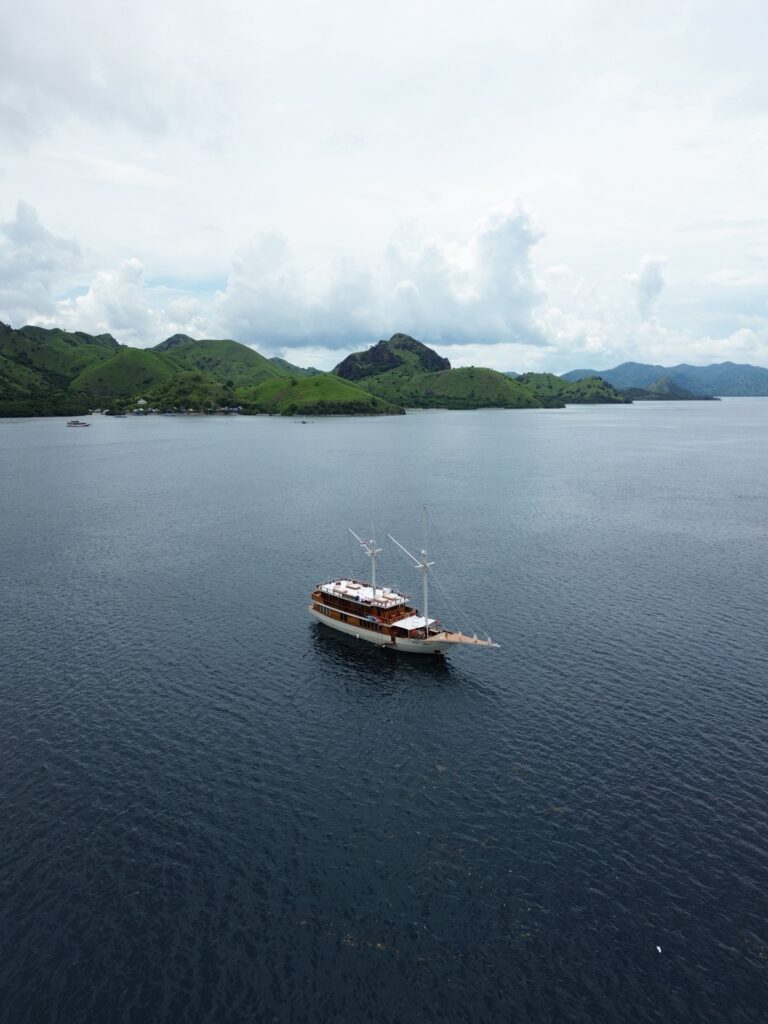 Boat cruising past rolling green islands under a bright cloudy sky near Manjarite Beach