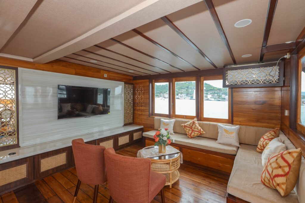 Indoor saloon with a flat screen TV, wraparound sofa and large windows
