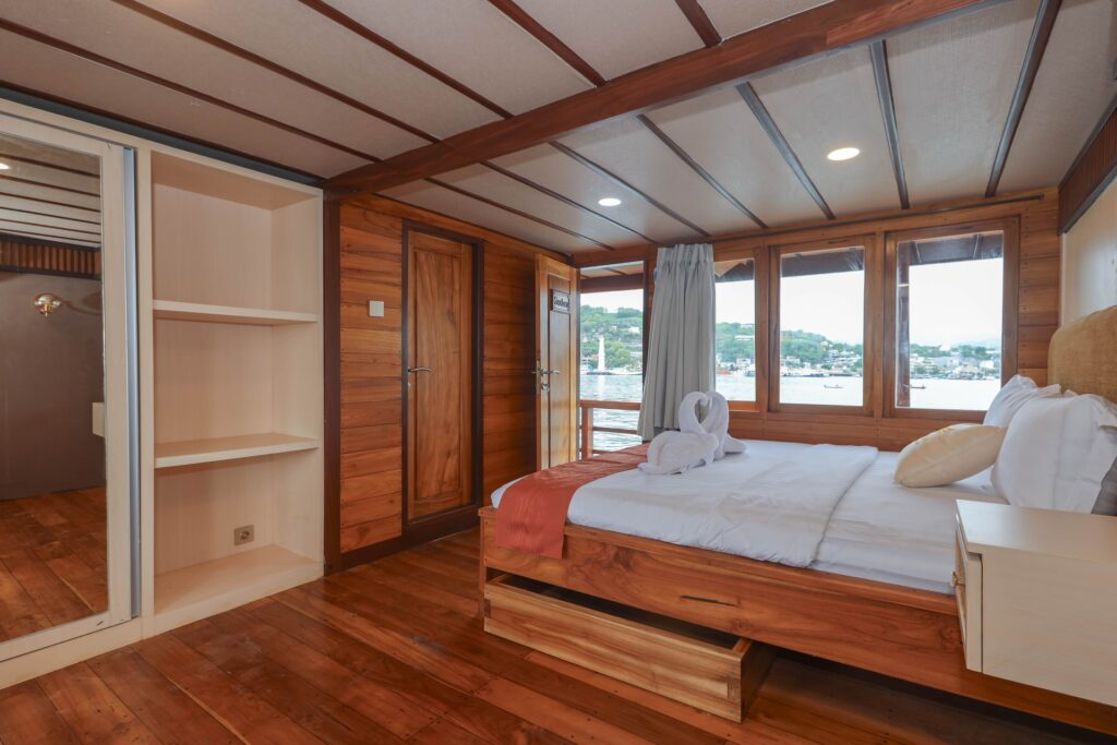 Elrora master suite bed with swan towel art beside large windows