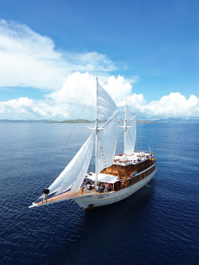 Elrora liveaboard phinisi sailing under full white sails on open water