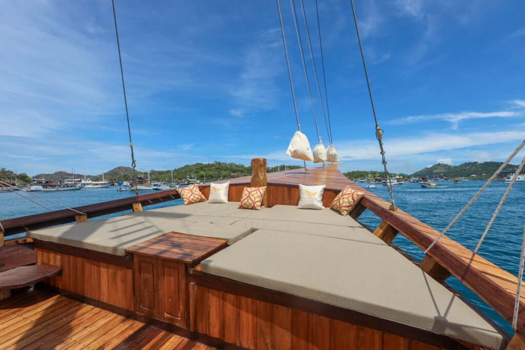 Sun lounging pads on the bow of a wooden yacht overlooking the ocean
