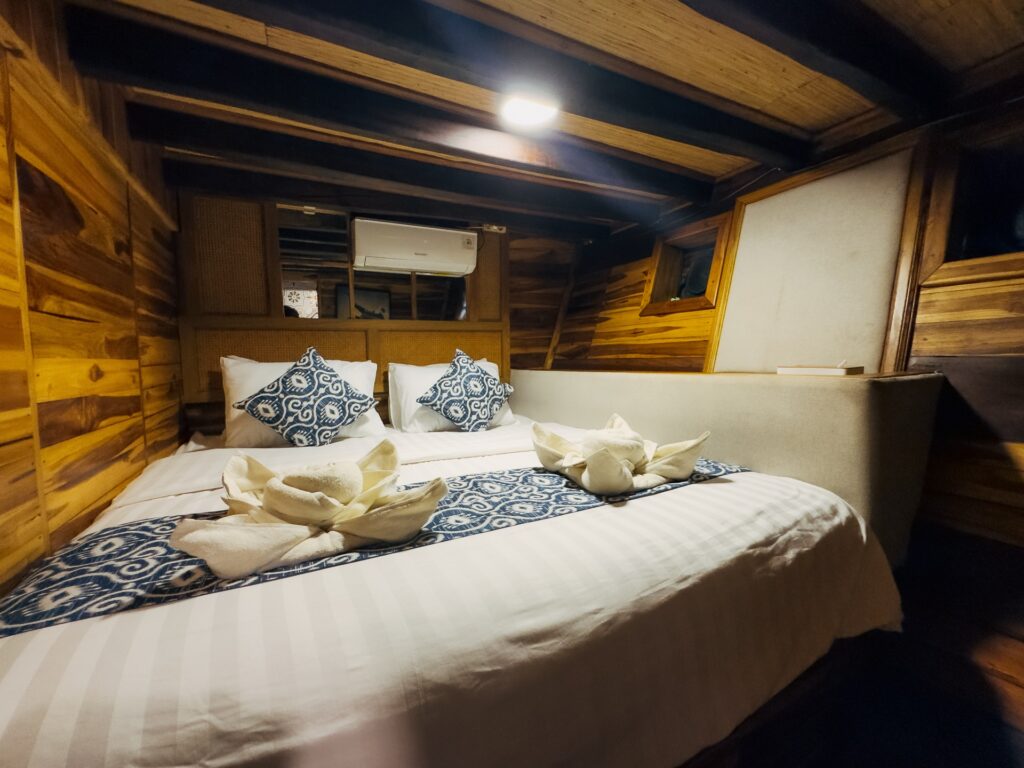 Deluxe cabin bed with decorative towel art and patterned pillows in a wood-paneled room