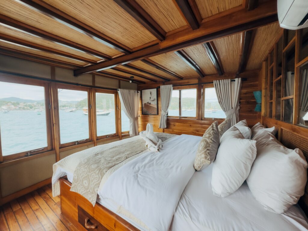Wood-paneled cabin aboard the Gammara with a large bed and ocean-view windows