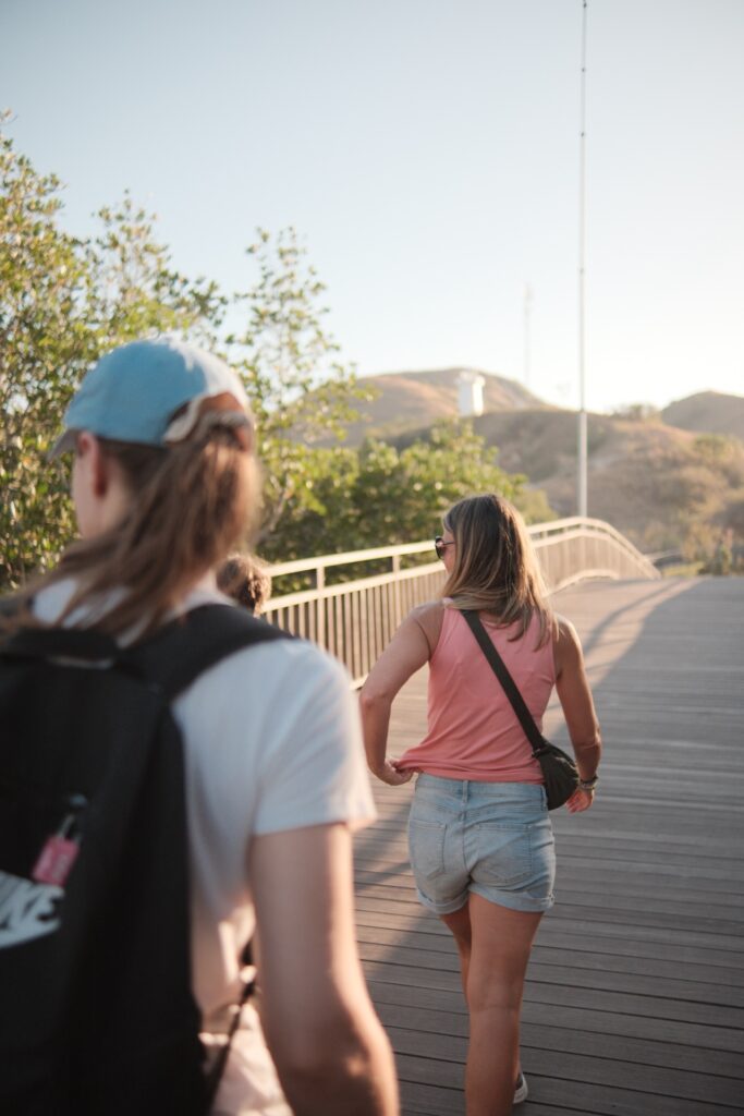 Two guests walking a wooden boardwalk trail during a golden hour trek