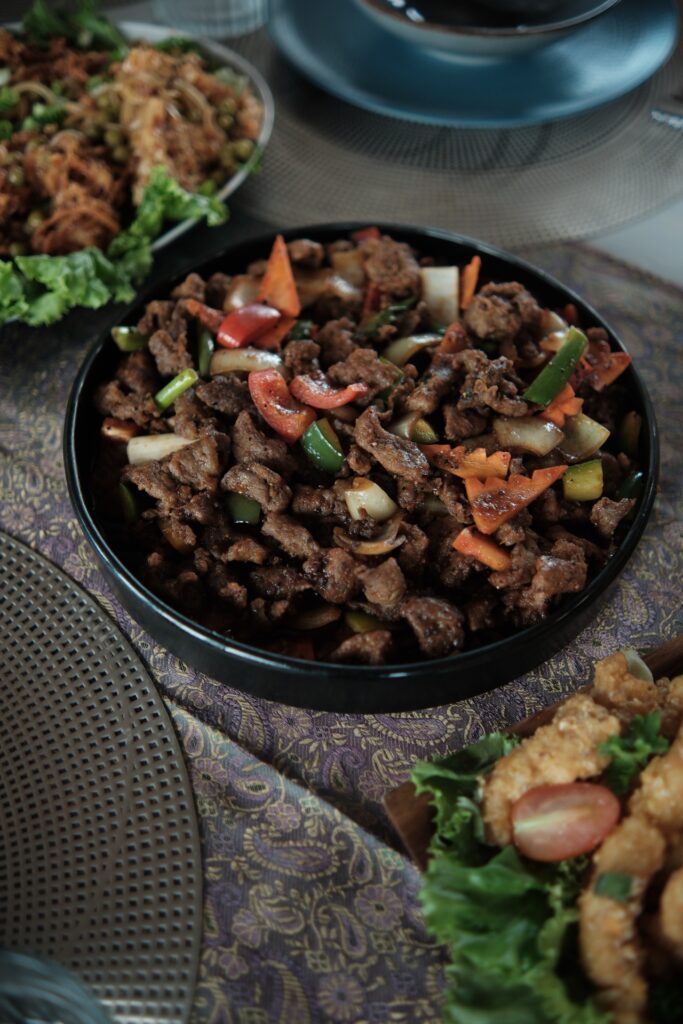 Close-up of a spiced stir-fried meat dish among an Indonesian dinner spread