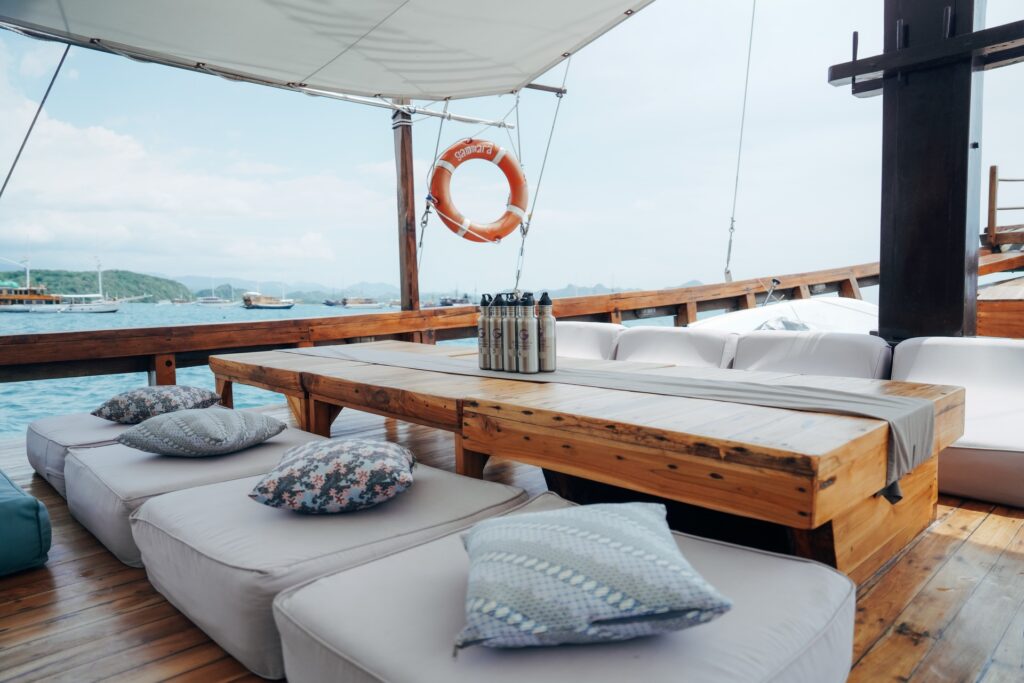White cushioned deck lounge seating around a low wooden table, life ring hanging nearby