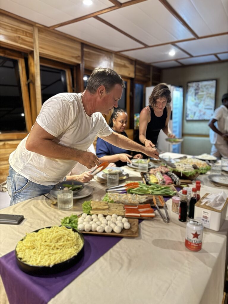 Guests serving themselves at an indoor buffet dinner spread on the Gammara