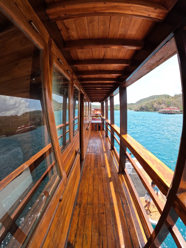 Narrow wooden side deck walkway lined with windows overlooking the sea