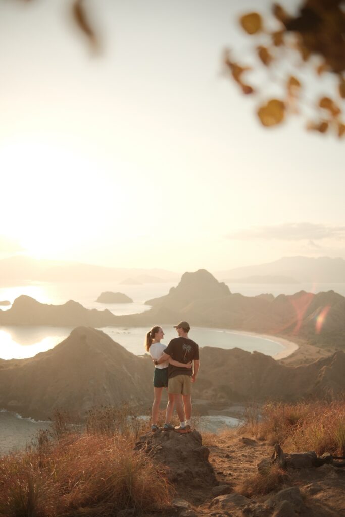 A couple watching the sunset over the islands from a hilltop viewpoint