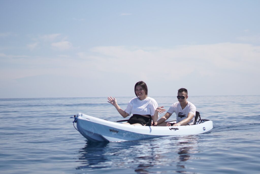 Two guests paddling a tandem kayak together on calm open water