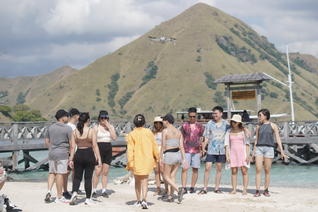 A group of guests gathered on a beach with dry hills rising behind