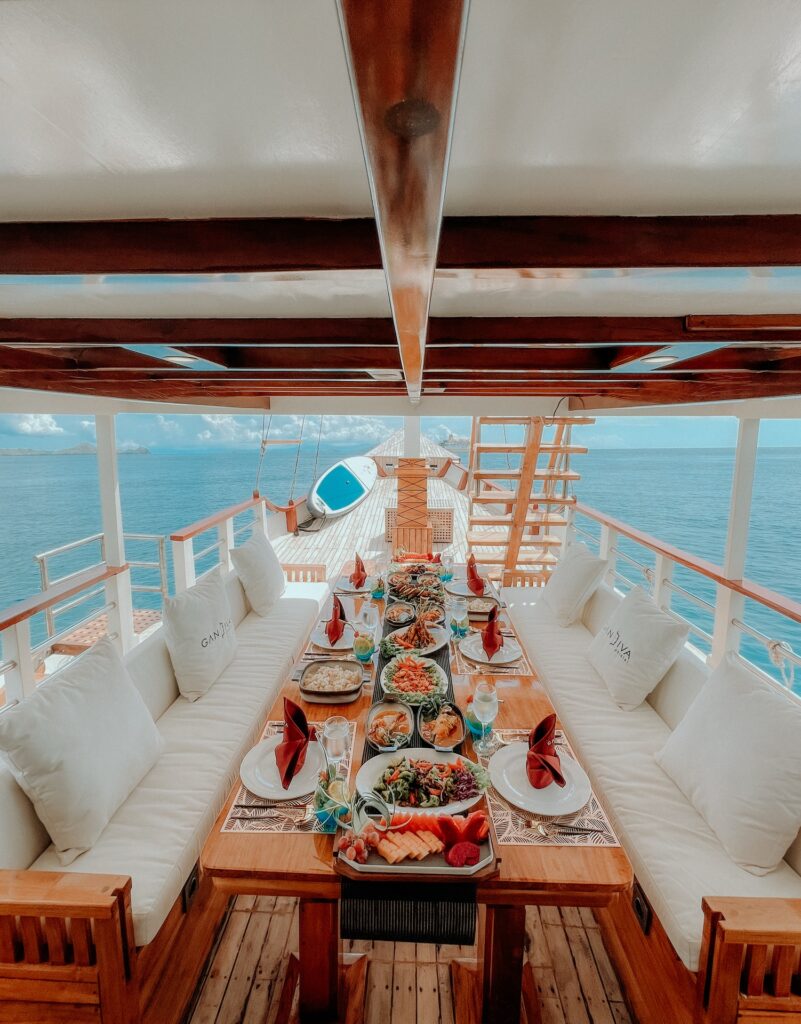 Long dining table set on deck with a tropical spread and bench seating