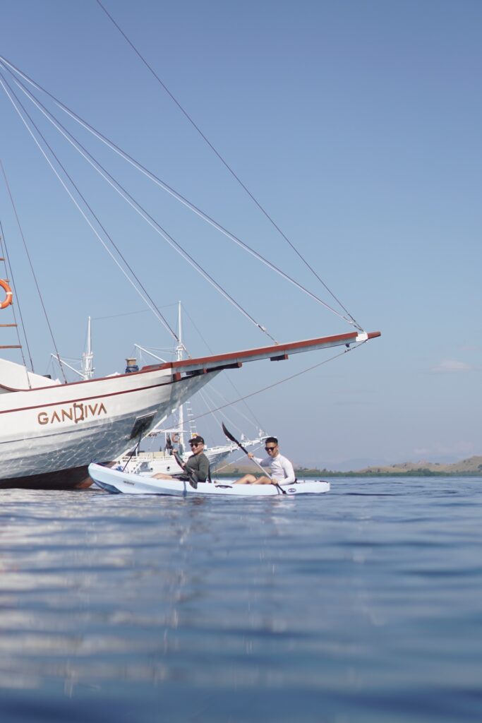 Guests kayaking beside the Gandiva bow in calm water