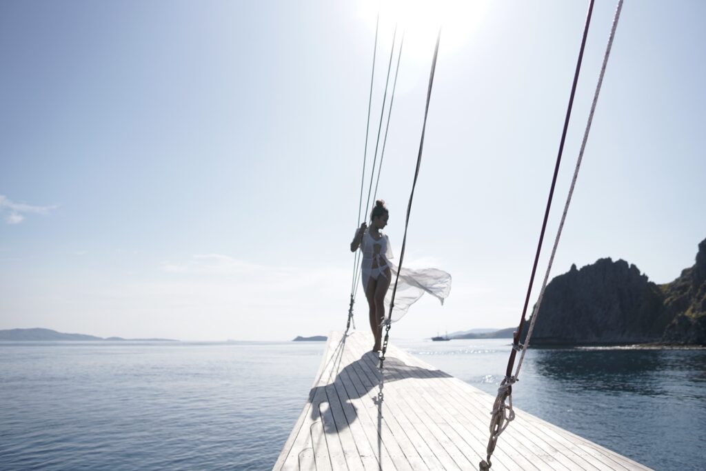A guest in a flowing wrap standing at the bow of the Gandiva in bright sun
