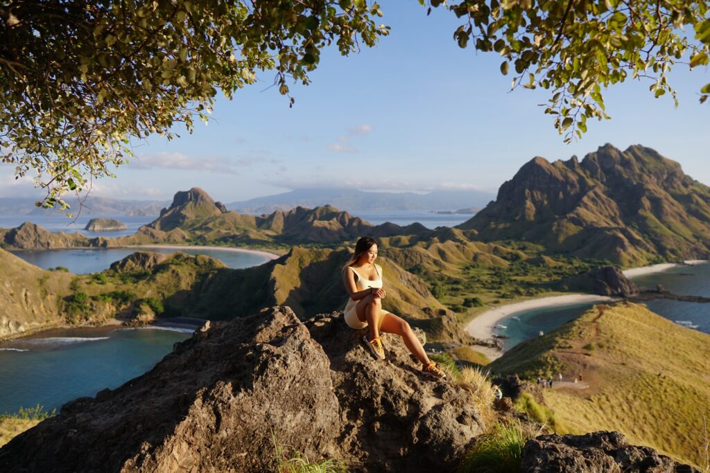 A guest sitting on a rocky outcrop above the three-bay view of Padar Island