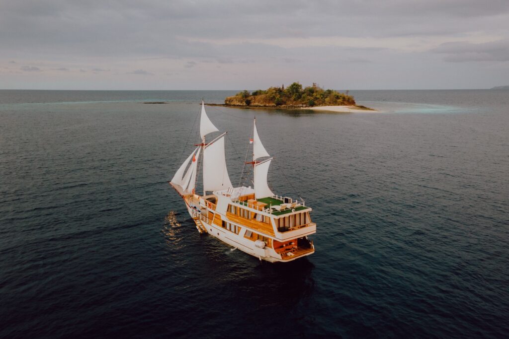 Sails furled near a small remote island under an overcast sky