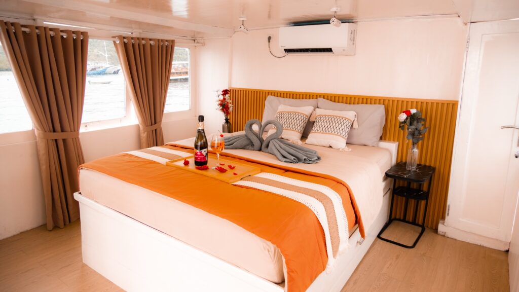 Master suite bed with orange linens, swan towel art, and a wine bottle