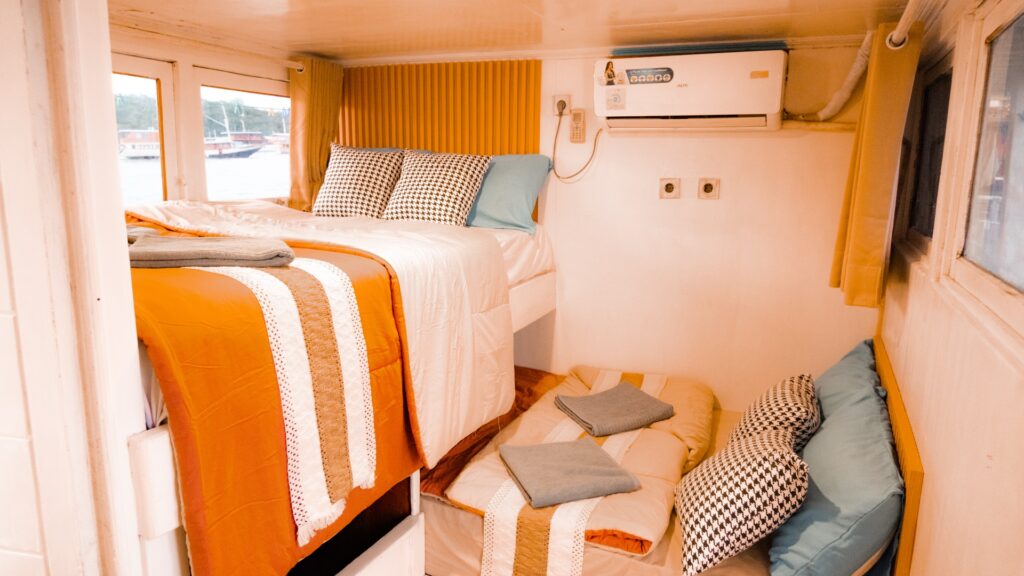 Shared cabin on the Giona with an orange bedspread and a small floor seating nook