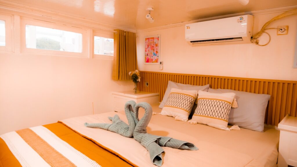 Deluxe suite bed with orange striped linens and a curled blue towel animal