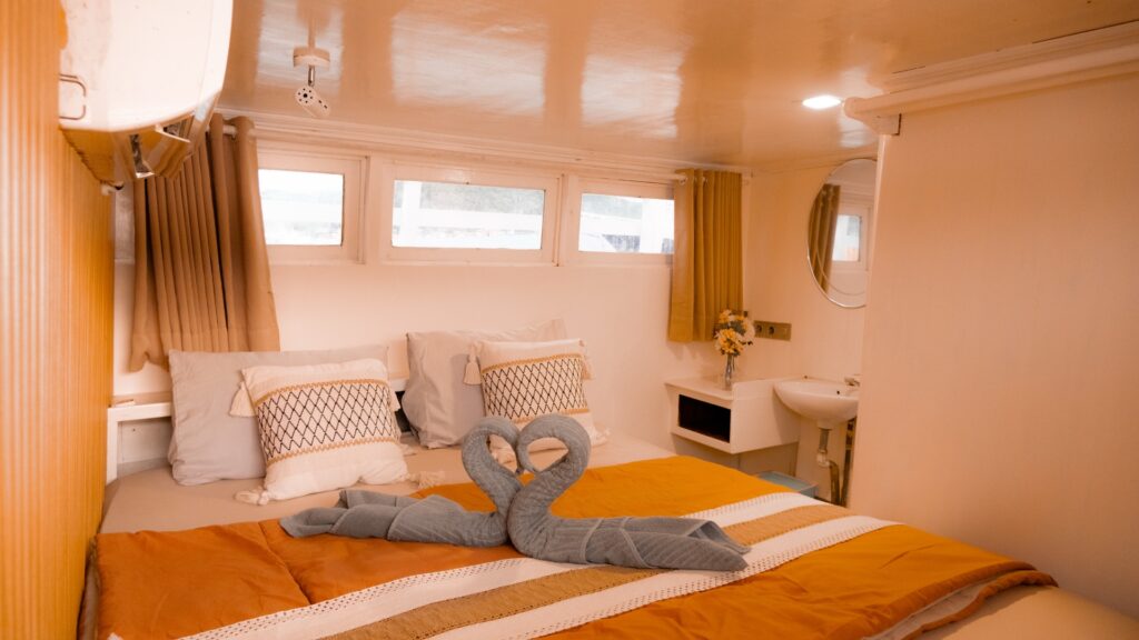 Deluxe cabin with orange linens, a blue towel animal, and symmetrical windows