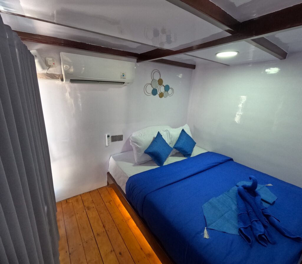 Deluxe Cabin with a blue bed, glossy white walls, and circular metal wall art