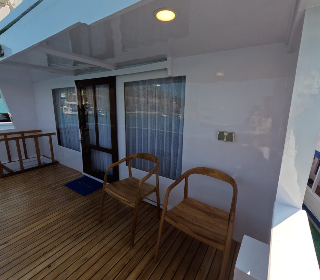 Private wooden balcony outside the Master Cabin with two chairs facing the sea