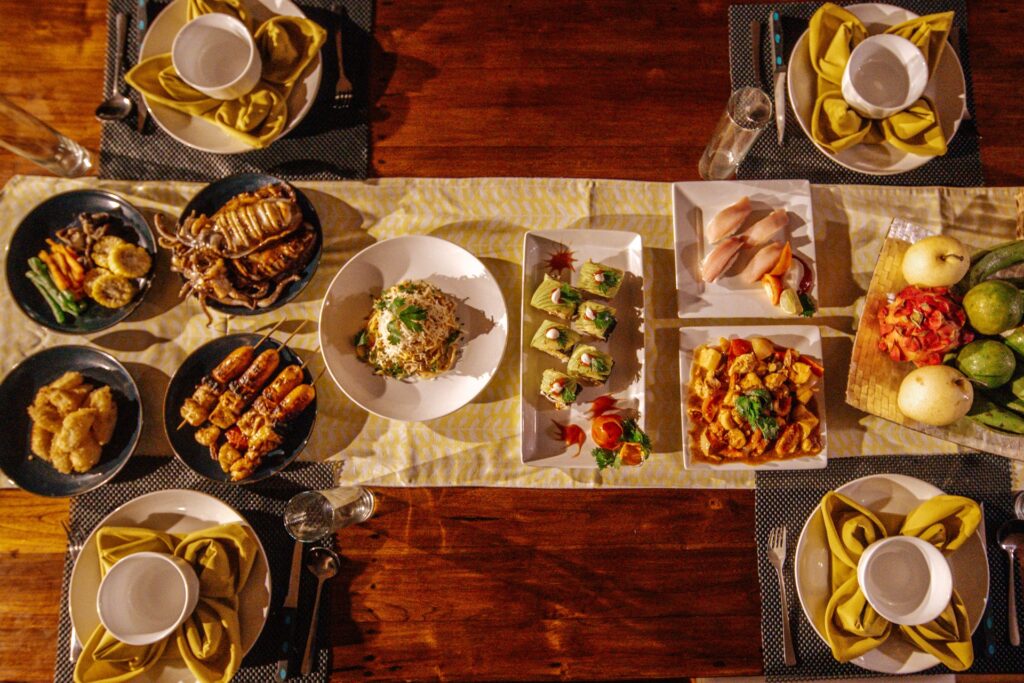 Top-down view of a dinner spread with grilled seafood, sushi, and fresh fruit