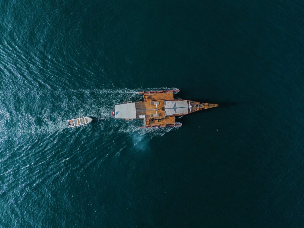 Overhead drone view of the Jofiel with its tender boat trailing a wake
