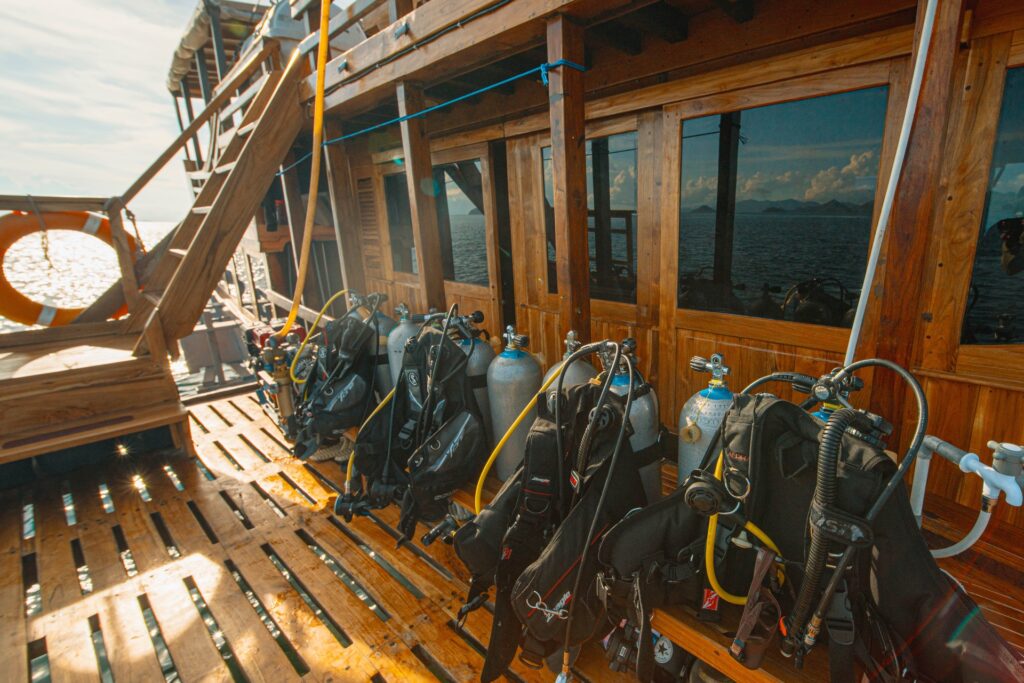 Scuba BCDs and regulators set up along the wooden deck for a dive