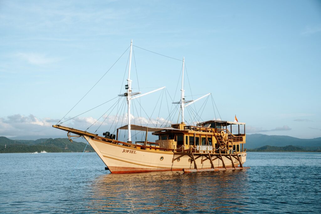 Jofiel phinisi anchored in calm water at golden hour, masts up