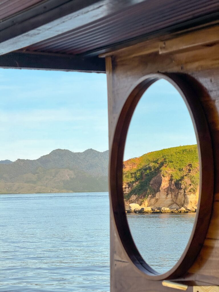 Round wooden-framed opening looking out to hills and coastline
