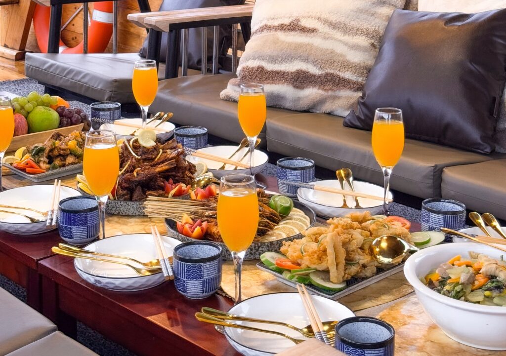Deck dining table set with orange drinks in champagne flutes and shared plates