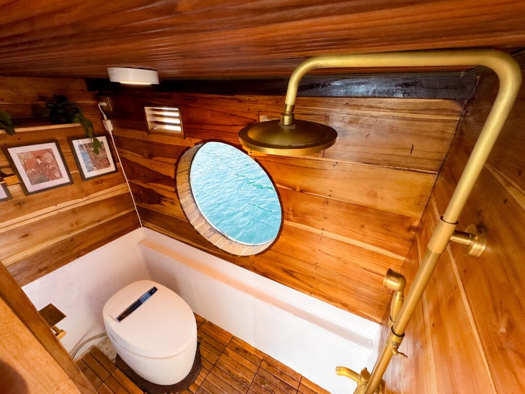 Wooden ensuite bathroom with brass shower fixtures and an oval porthole