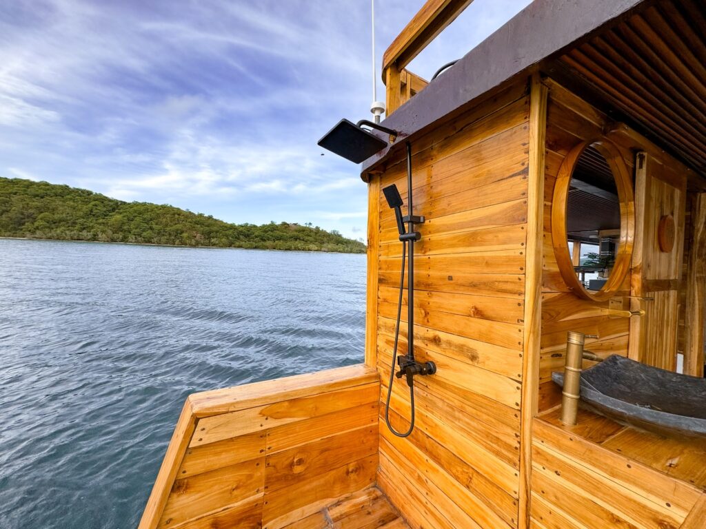 Outdoor wooden shower at the stern overlooking the water and hills