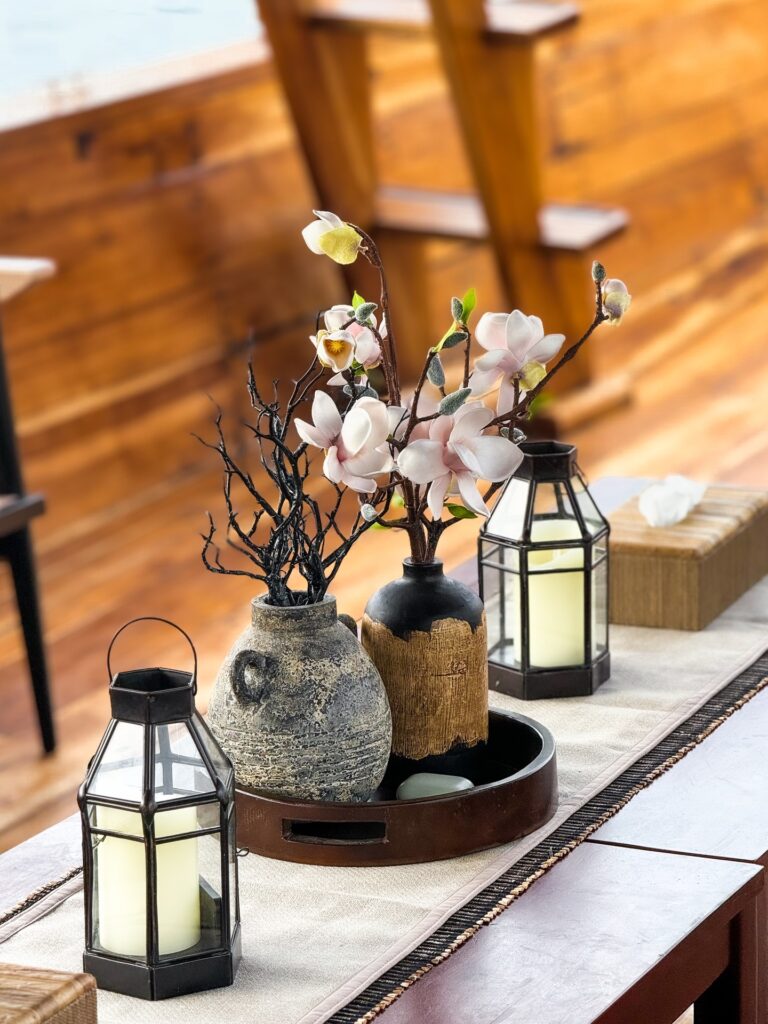 Table decor with flowering branches in vases and small glass lanterns