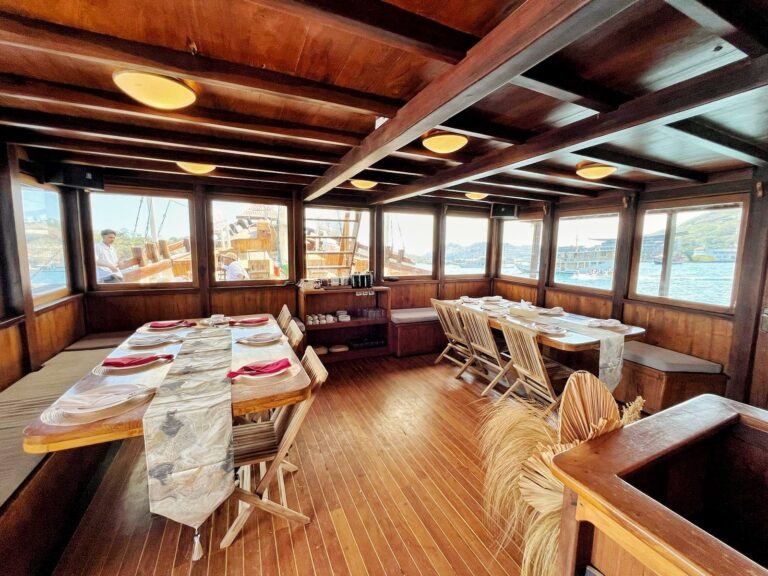 Restaurant cabin with tables set for a group meal beside harbor windows