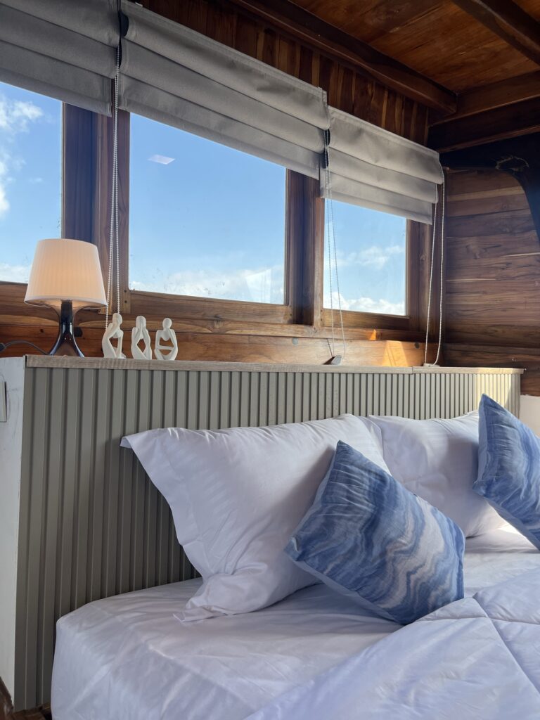 Master suite bed with white and blue linens beneath a row of windows