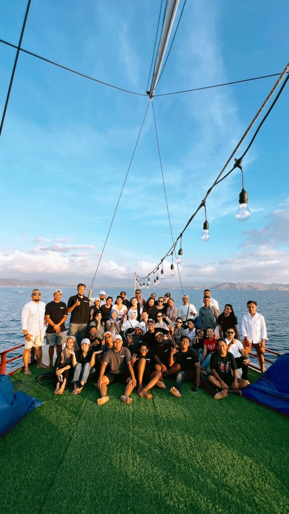 A large group of guests posing together on deck at dusk