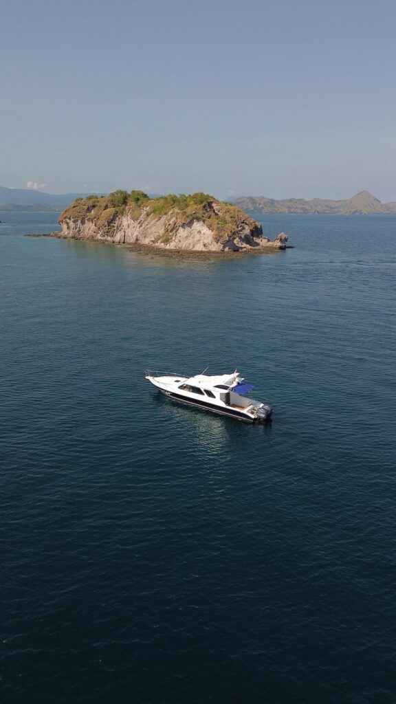 Ocean Manta anchored near a small island, aerial view over blue water