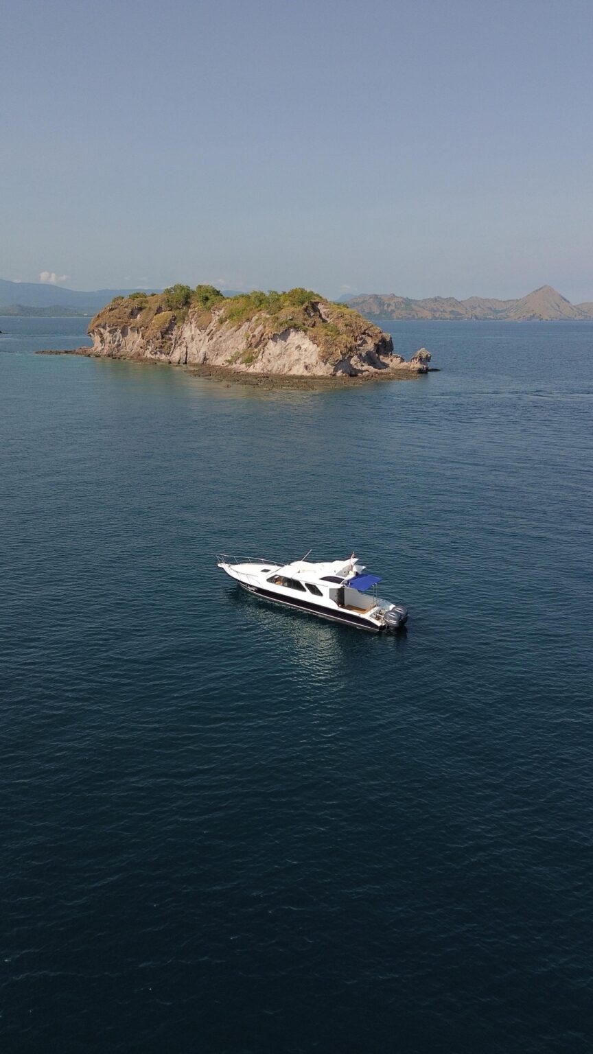 Ocean Manta anchored near a small island, aerial view over blue water
