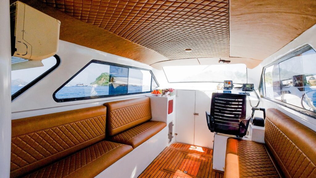 Shaded cabin aboard Ocean Manta with quilted leather benches and teak ceiling