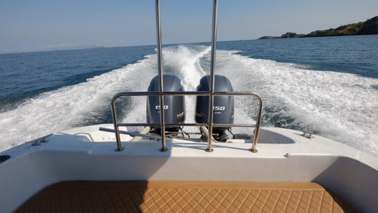 Twin outboard engines churn a white wake behind the Ocean Manta speedboat