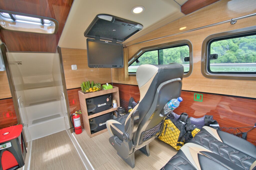 Rear cabin nook with a single seat, TV screen, and storage shelf