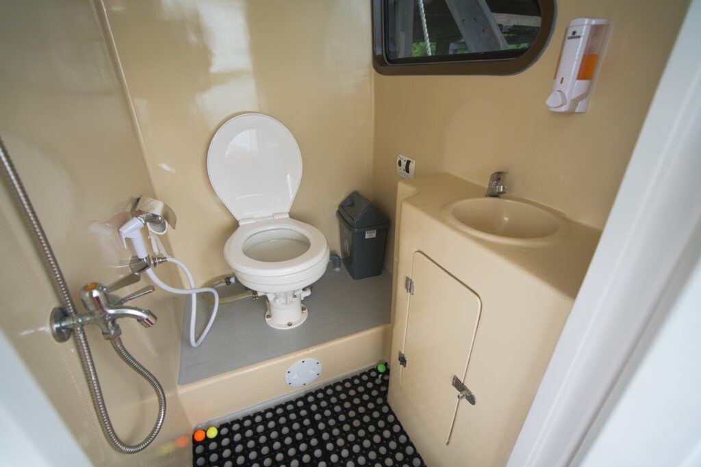 Compact onboard washroom with toilet, sink, and hand-held shower