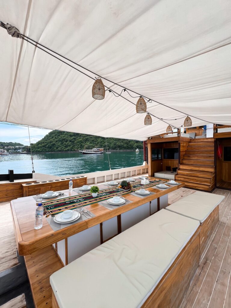 Shaded alfresco dining table set on Panrita's main deck overlooking the harbor
